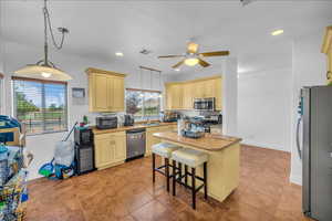 Kitchen with stainless steel appliances, a center island, hanging light fixtures, a kitchen breakfast bar, and ceiling fan