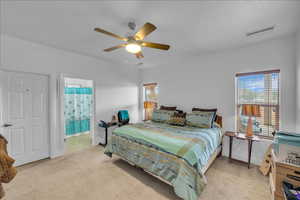Bedroom with light carpet, multiple windows, and ceiling fan