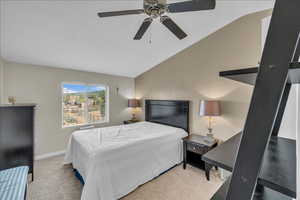 Bedroom featuring light colored carpet, lofted ceiling, and ceiling fan