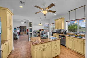 Kitchen with cream cabinets, ceiling fan, a kitchen island, and decorative light fixtures