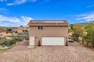 Back of house with a mountain view, roof mounted solar panels, and stucco siding