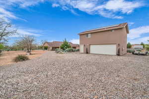 Back of house featuring stucco siding, solar panels, driveway, and a garage