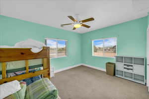Bedroom with multiple windows, light carpet, and a ceiling fan