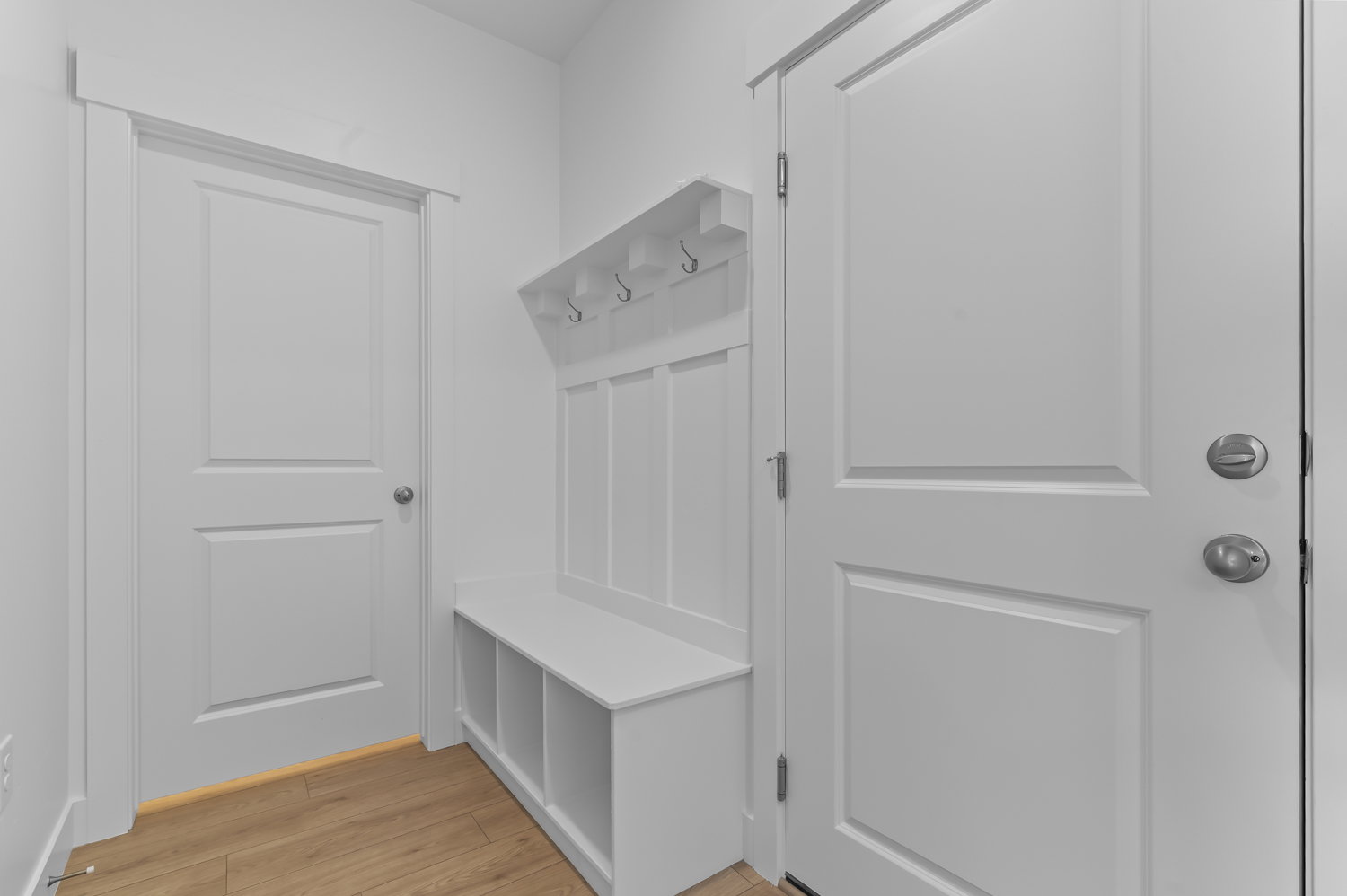 Entryway featuring light wood-finish flooring, white walls, and a built-in bench with storage cubbies