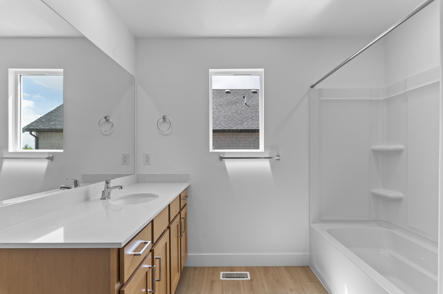 Bathroom featuring a light wood-finish vanity with an integrated sink, polished chrome faucet, and expansive wall-mounted mirror