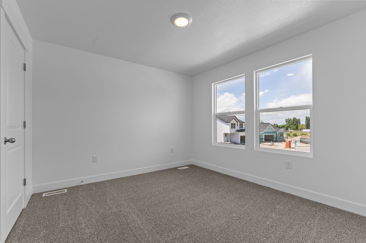 Bright interior space featuring a recessed ceiling light, two large double-hung windows, white walls, and plush carpet flooring