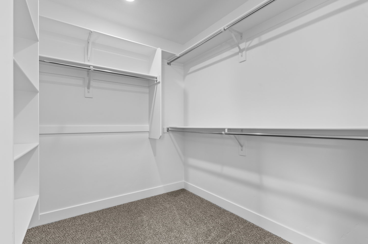 Walk-in closet featuring built-in shelving, multiple hanging rods, recessed lighting, white baseboards, and carpeted flooring