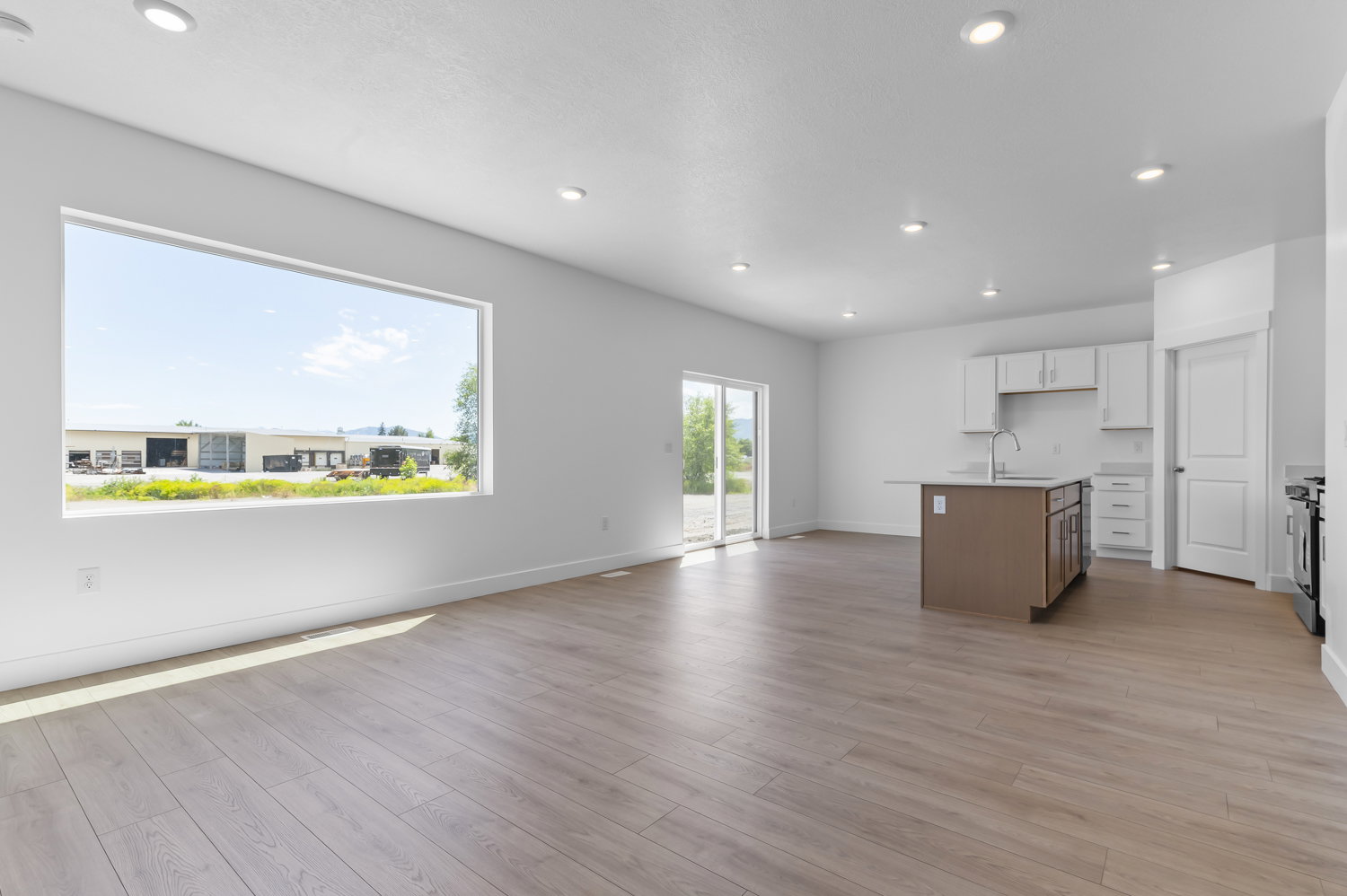 Open-concept living space featuring wood-finish flooring, recessed lighting, and a large picture window
