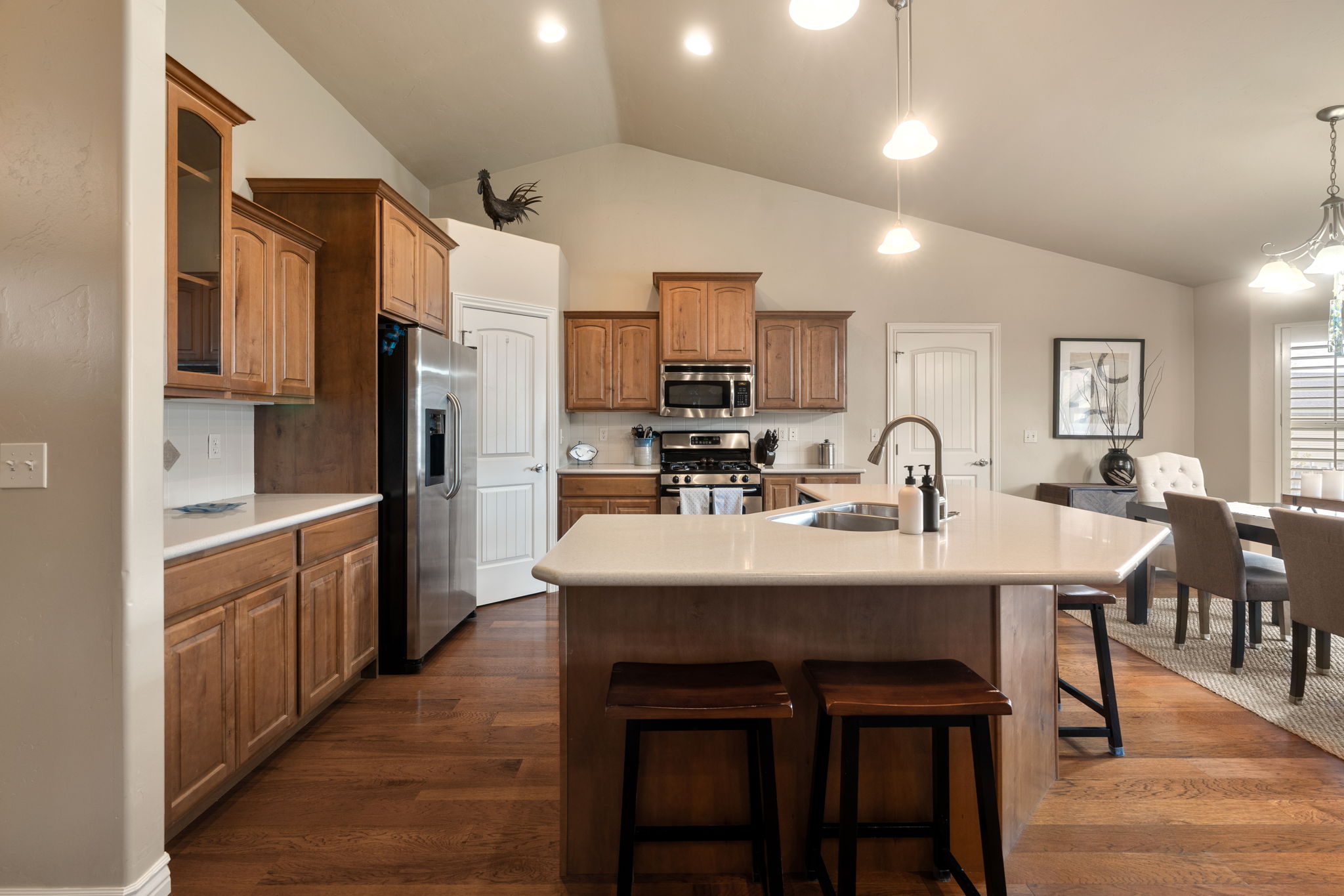 Kitchen featuring light countertops, wood finish cabinets, an island with sink, a kitchen bar, and stainless steel appliances