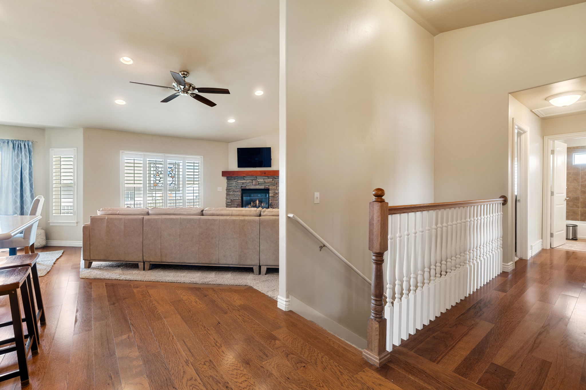 Living room with hardwood / wood-style floors, a stone fireplace, recessed lighting, and ceiling fan