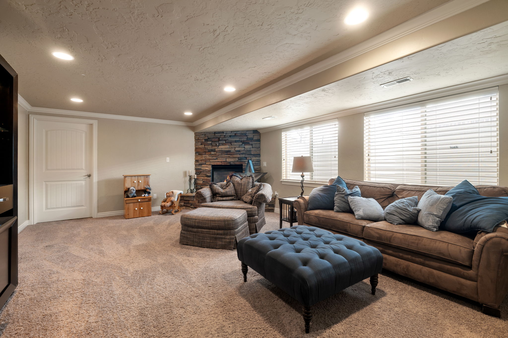 Living room with ornamental molding, carpet, a textured ceiling, a fireplace, and recessed lighting