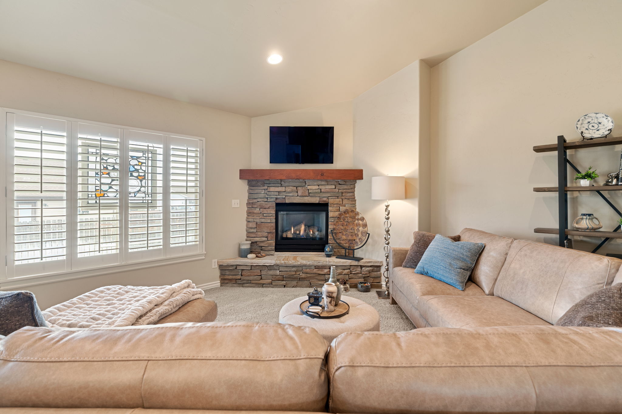 Living room featuring carpet floors, lofted ceiling, and a stone fireplace