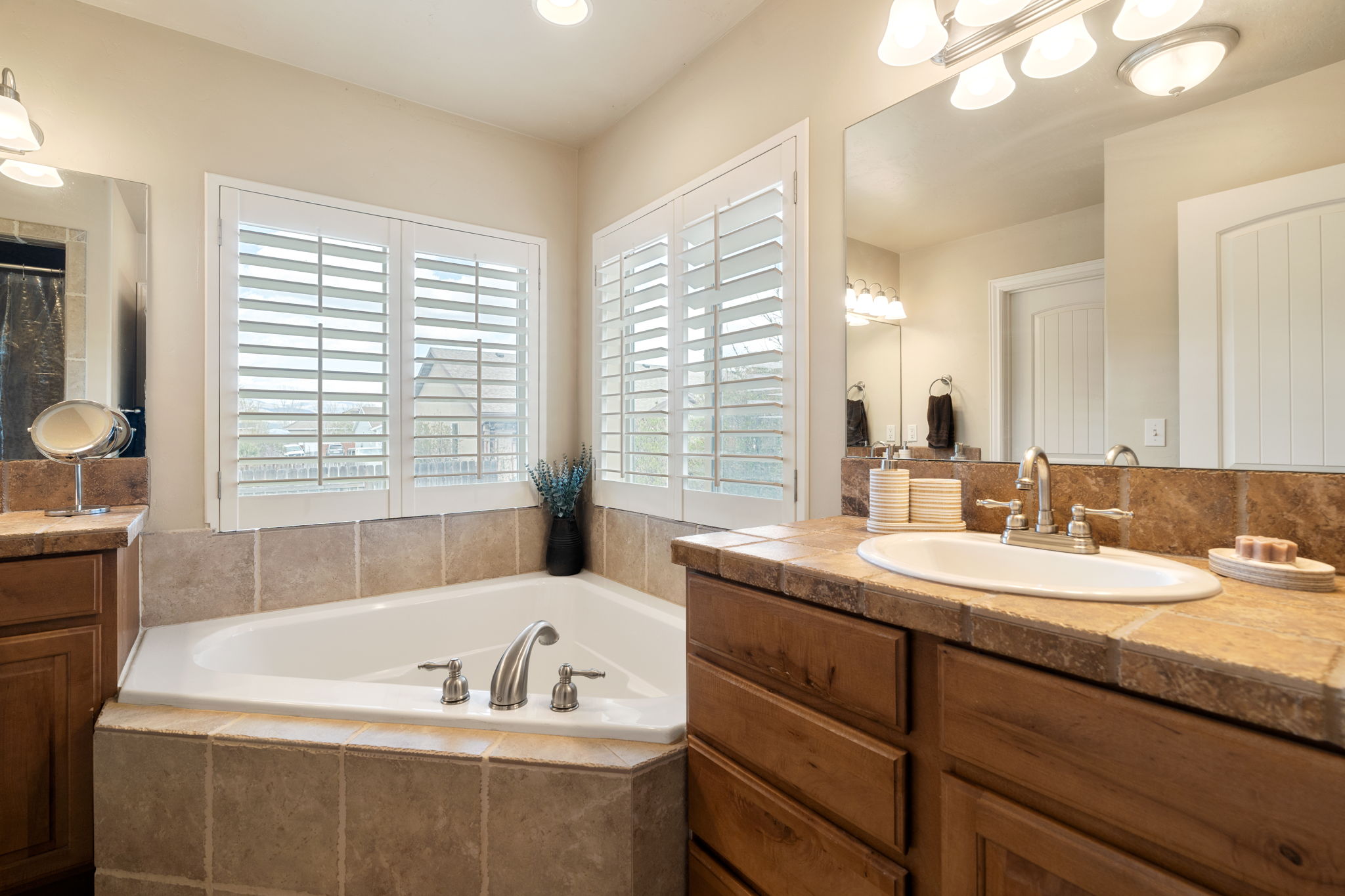 Bathroom featuring two vanities, a garden tub, and curtained shower