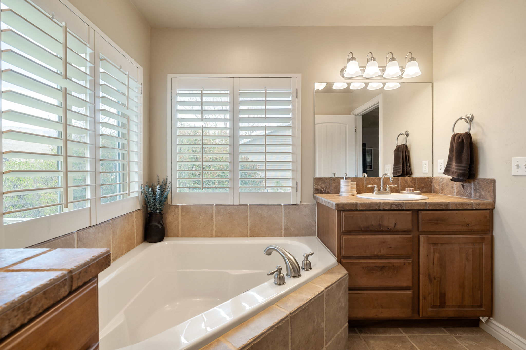 Bathroom featuring vanity, a garden tub, and dark tile patterned floors
