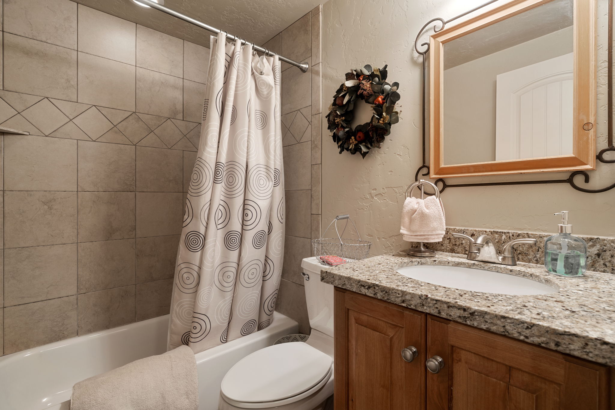 Full bathroom featuring a textured wall, vanity, and shower / tub combo with curtain