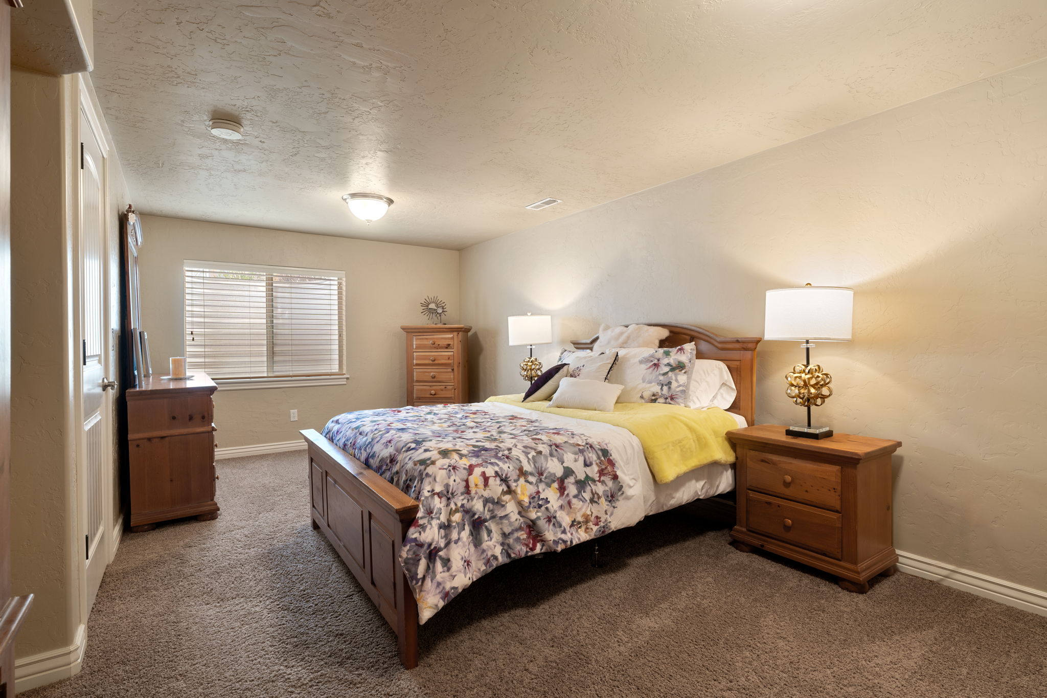 Bedroom with a textured ceiling, dark carpet, and a textured wall