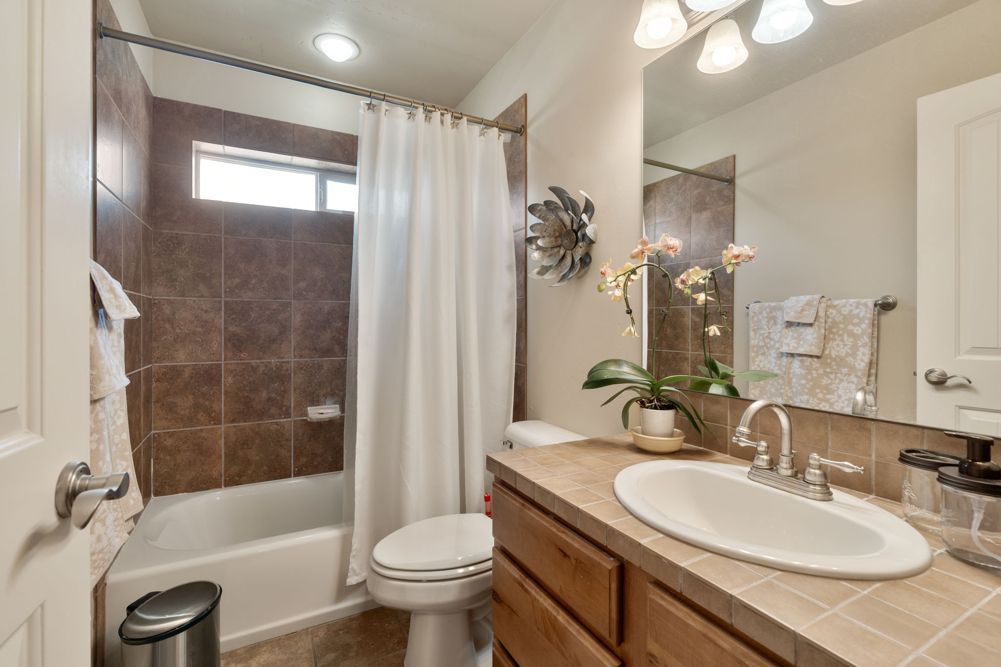 Bathroom with vanity, shower / bath combination with curtain, and dark tile patterned flooring