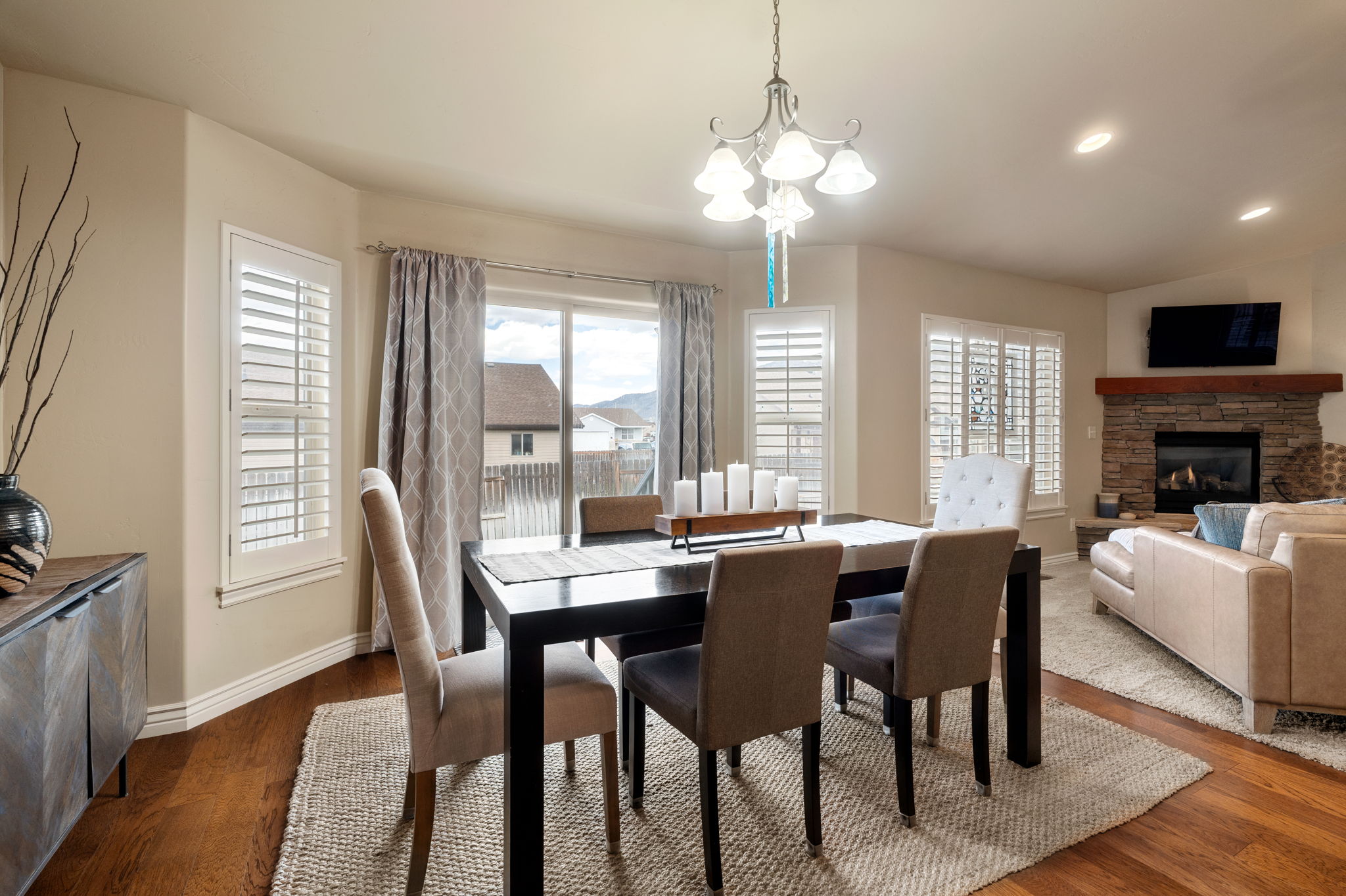 Dining area with vaulted ceiling, hanging lights, dark wood-type flooring, and a fireplace