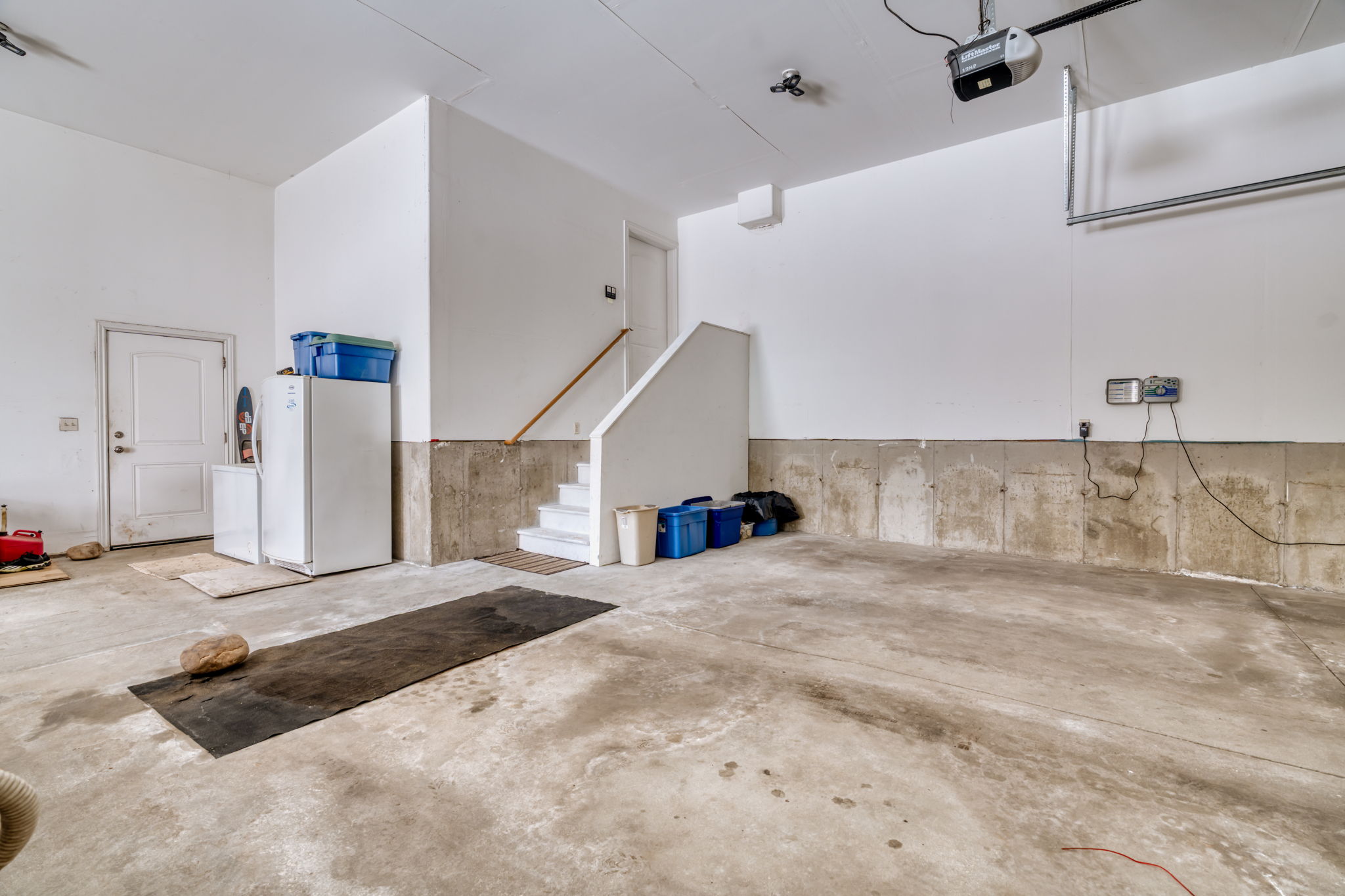 Garage with freestanding refrigerator and a garage door opener