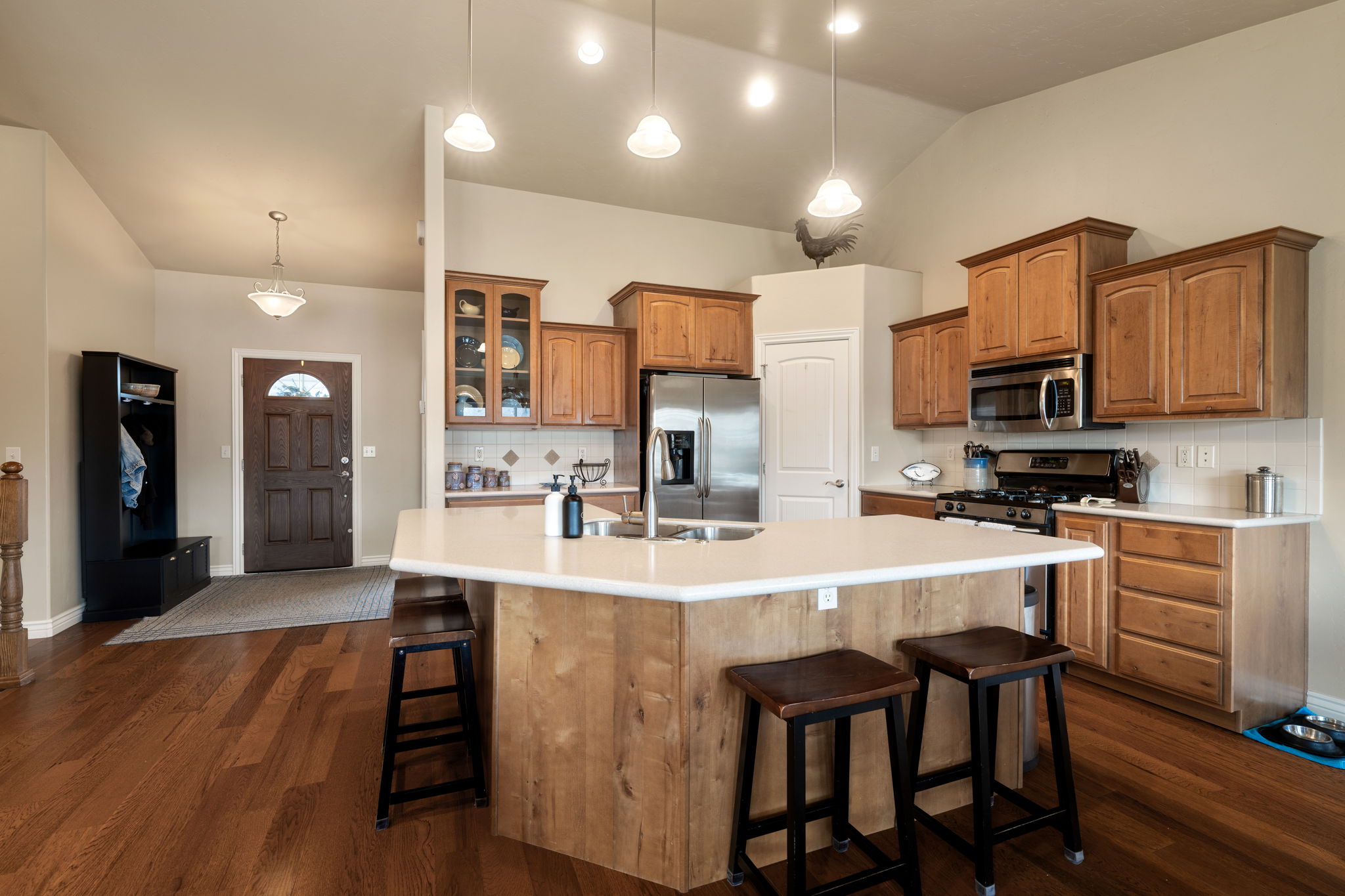 Kitchen featuring wood finish cabinetry, a kitchen breakfast bar, stainless steel appliances, a large island with sink, and vaulted ceiling