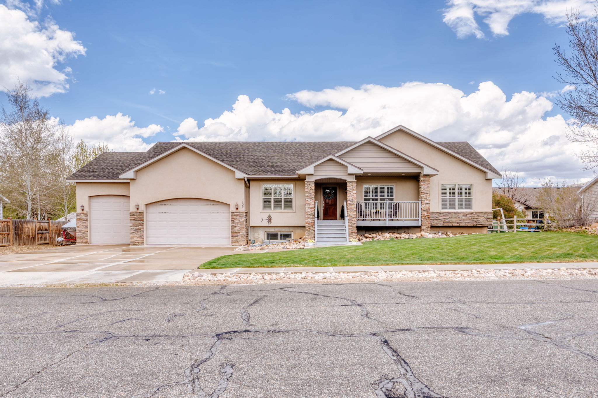 View of front of property featuring an attached garage, stucco siding, stone siding, and roof with shingles