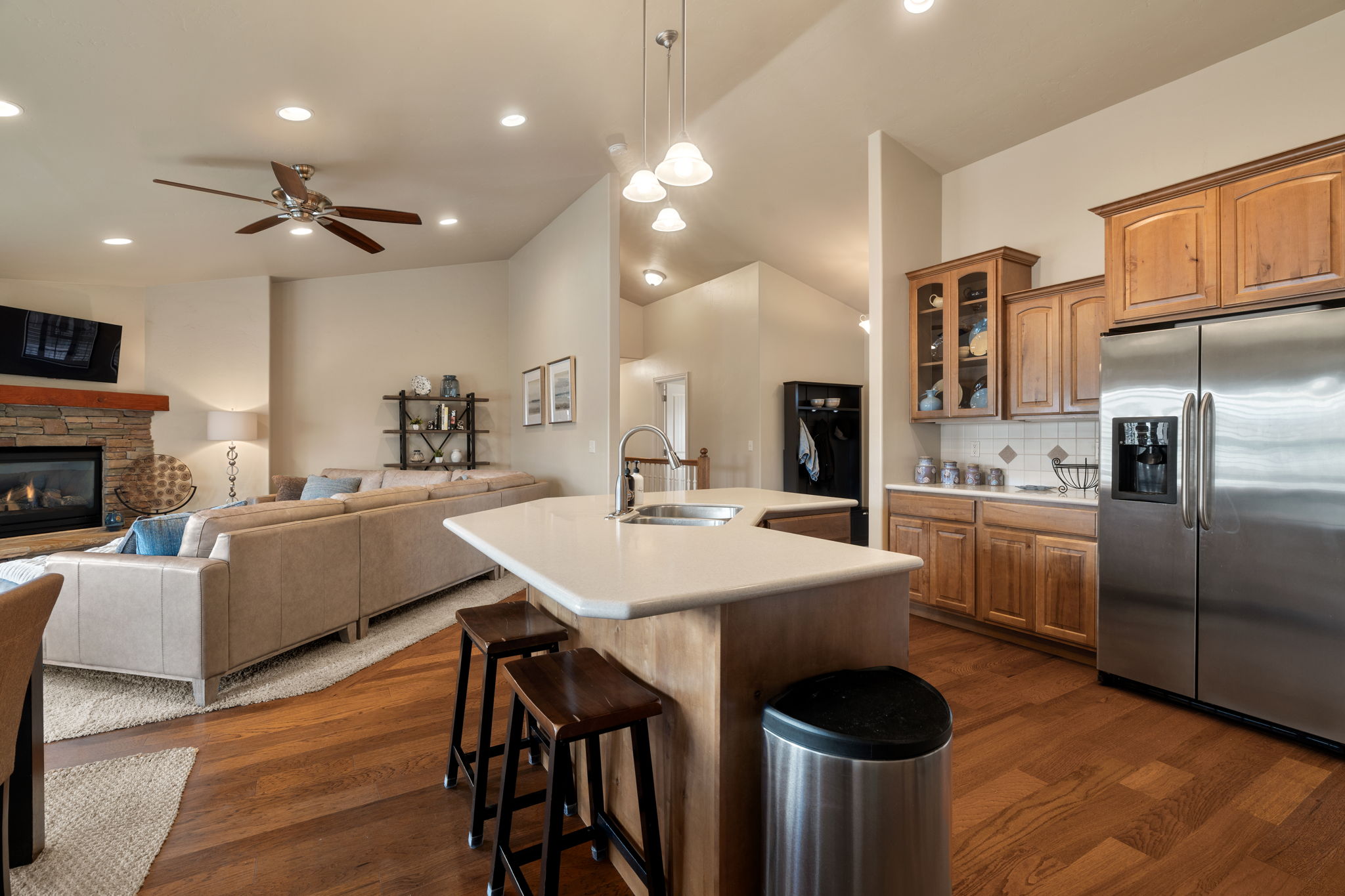 Kitchen featuring stainless steel refrigerator with ice dispenser, open floor plan, light countertops, a kitchen bar, and dark wood-style flooring