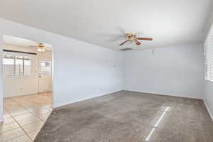 Spare room with ceiling fan, light tile patterned floors, and light colored carpet