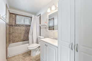 Bathroom with vanity, shower / tub combo with curtain, and light tile patterned floors