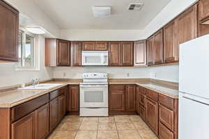 Kitchen featuring white appliances, light countertops, and light tile patterned floors