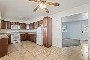 Kitchen featuring a ceiling fan, white appliances, light tile patterned flooring, a textured ceiling, and light carpet