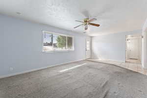 Unfurnished room featuring light colored carpet, ceiling fan, and a textured ceiling