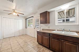 Kitchen with a textured ceiling, dark wood finish cabinets, ceiling fan, and light tile patterned flooring