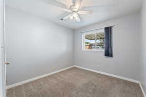 Empty room with a ceiling fan and carpet floors