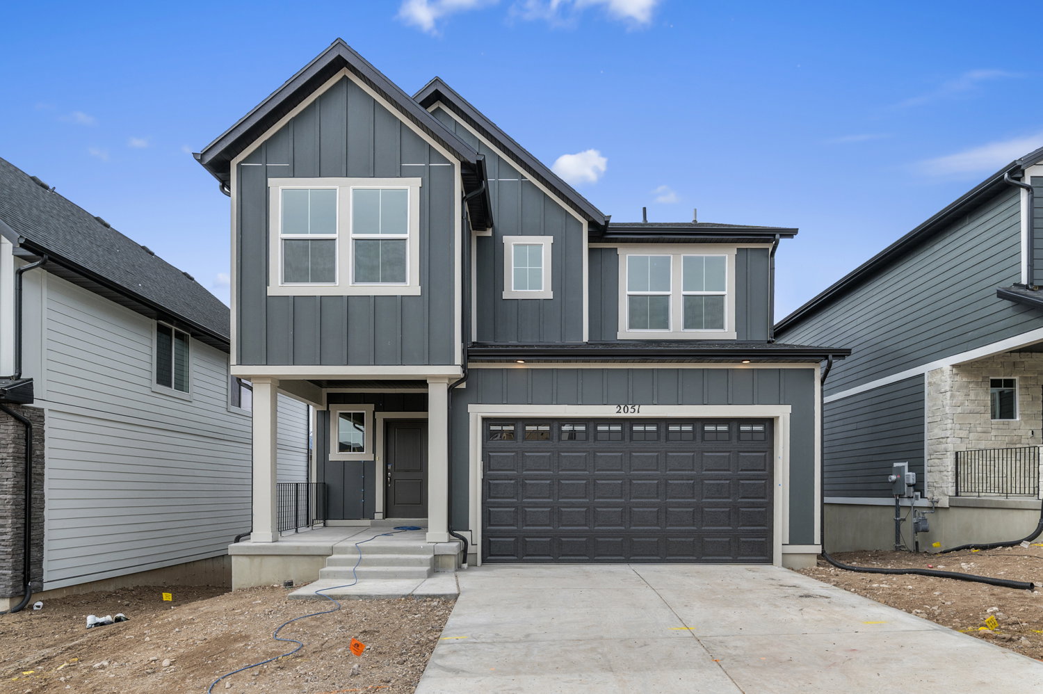 View of front facade with board and batten siding, an attached garage, and driveway