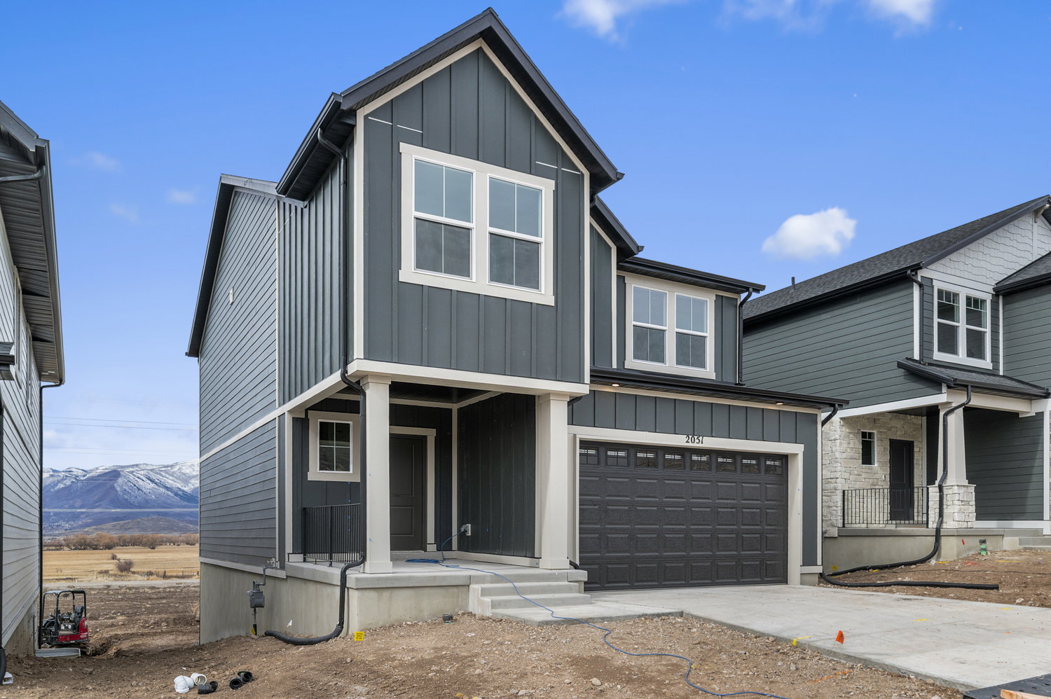 View of front of property with board and batten siding, a garage, concrete driveway, and a mountain view