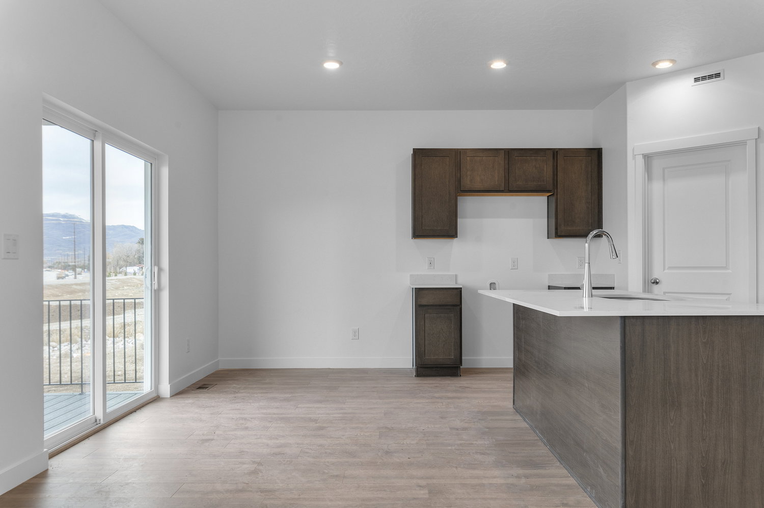 Kitchen with dark wood finish cabinets, a mountain view, light wood-style floors, recessed lighting, and light stone countertops