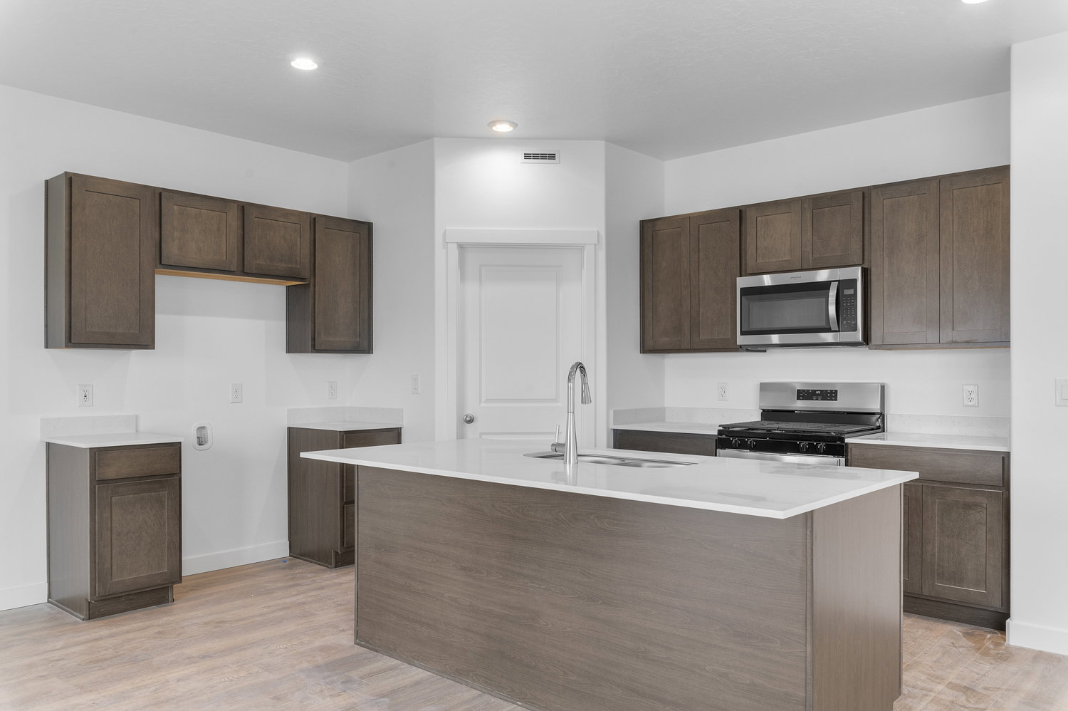 Kitchen featuring stainless steel appliances, a center island with sink, light wood-style flooring, recessed lighting, and light stone counters