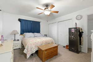 Carpeted bedroom with multiple closets and ceiling fan