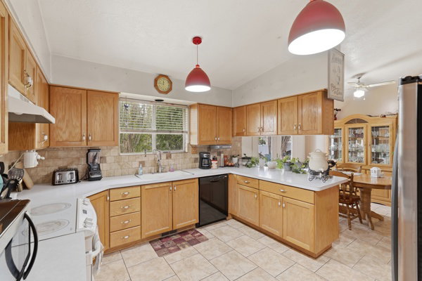 Kitchen with light countertops, lofted ceiling, a peninsula, electric stove, and freestanding refrigerator