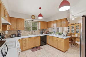 Kitchen with light countertops, lofted ceiling, a peninsula, electric stove, and freestanding refrigerator