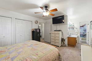 Bedroom featuring two closets, light colored carpet, and a ceiling fan