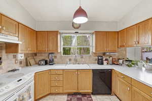 Kitchen with white range with electric cooktop, light countertops, black dishwasher, hanging light fixtures, and backsplash