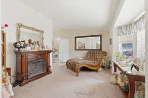 Living area featuring carpet, a glass covered fireplace, and lofted ceiling