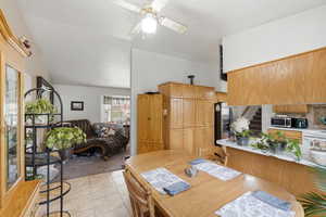 Kitchen with light countertops, lofted ceiling, ceiling fan, light tile patterned floors, and backsplash