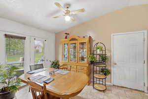 Dining area featuring vaulted ceiling, a ceiling fan, and light tile patterned floors