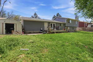 Back of house featuring a storage shed, a yard, french doors, and a deck