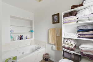 Bathroom with a jetted tub and baseboards
