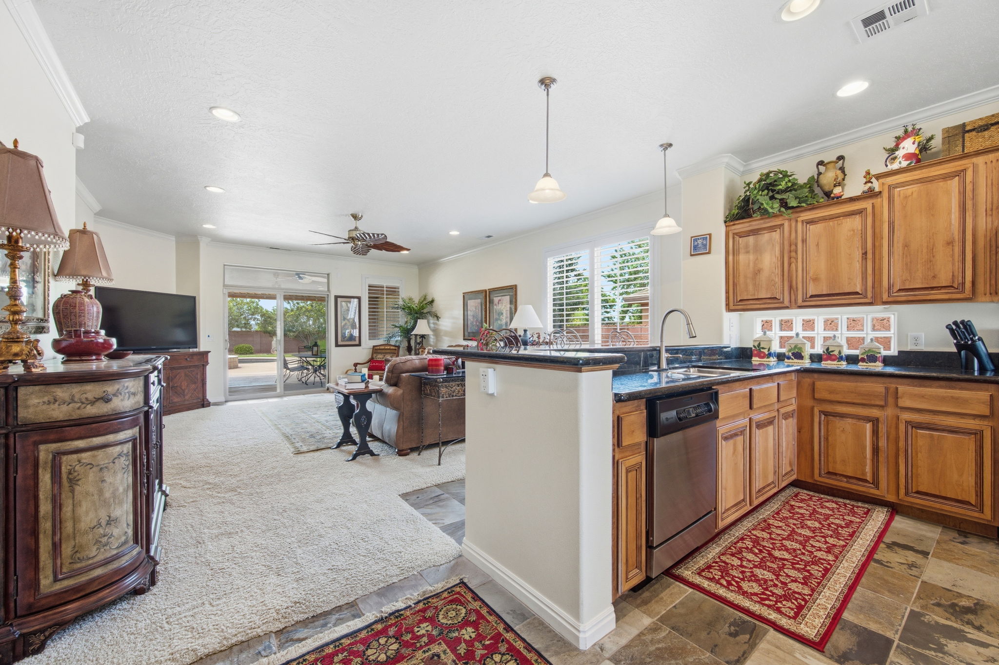 Kitchen featuring wood finish cabinetry, open floor plan, a peninsula, pendant lighting, and ceiling fan