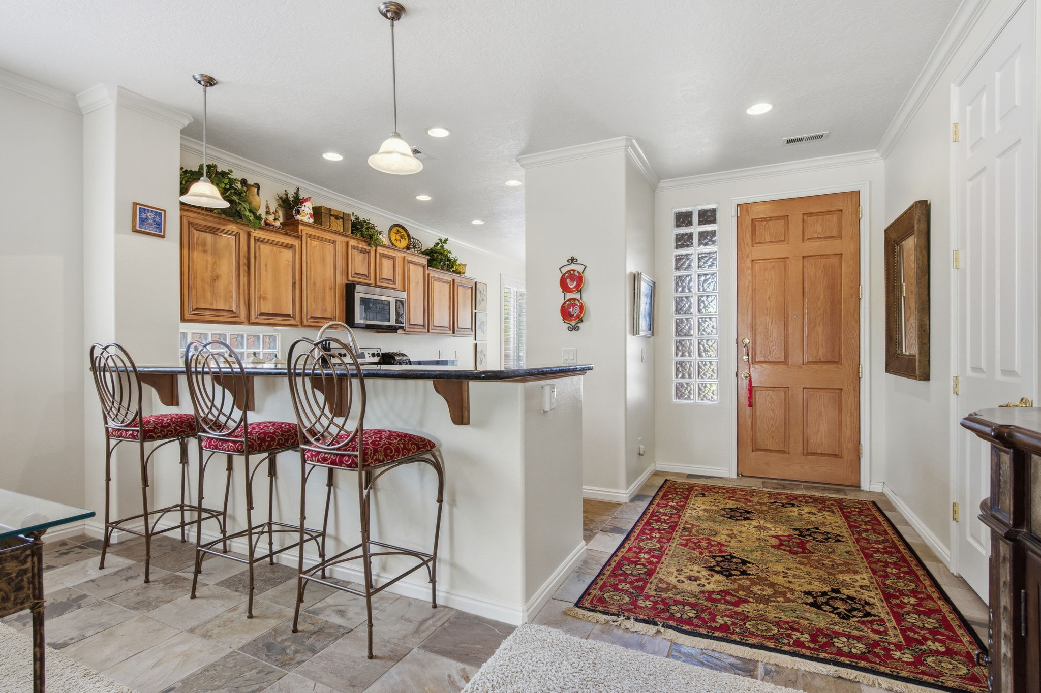 Kitchen featuring wood finish cabinetry, a breakfast bar, a peninsula, light stone finish flooring, and ornamental molding