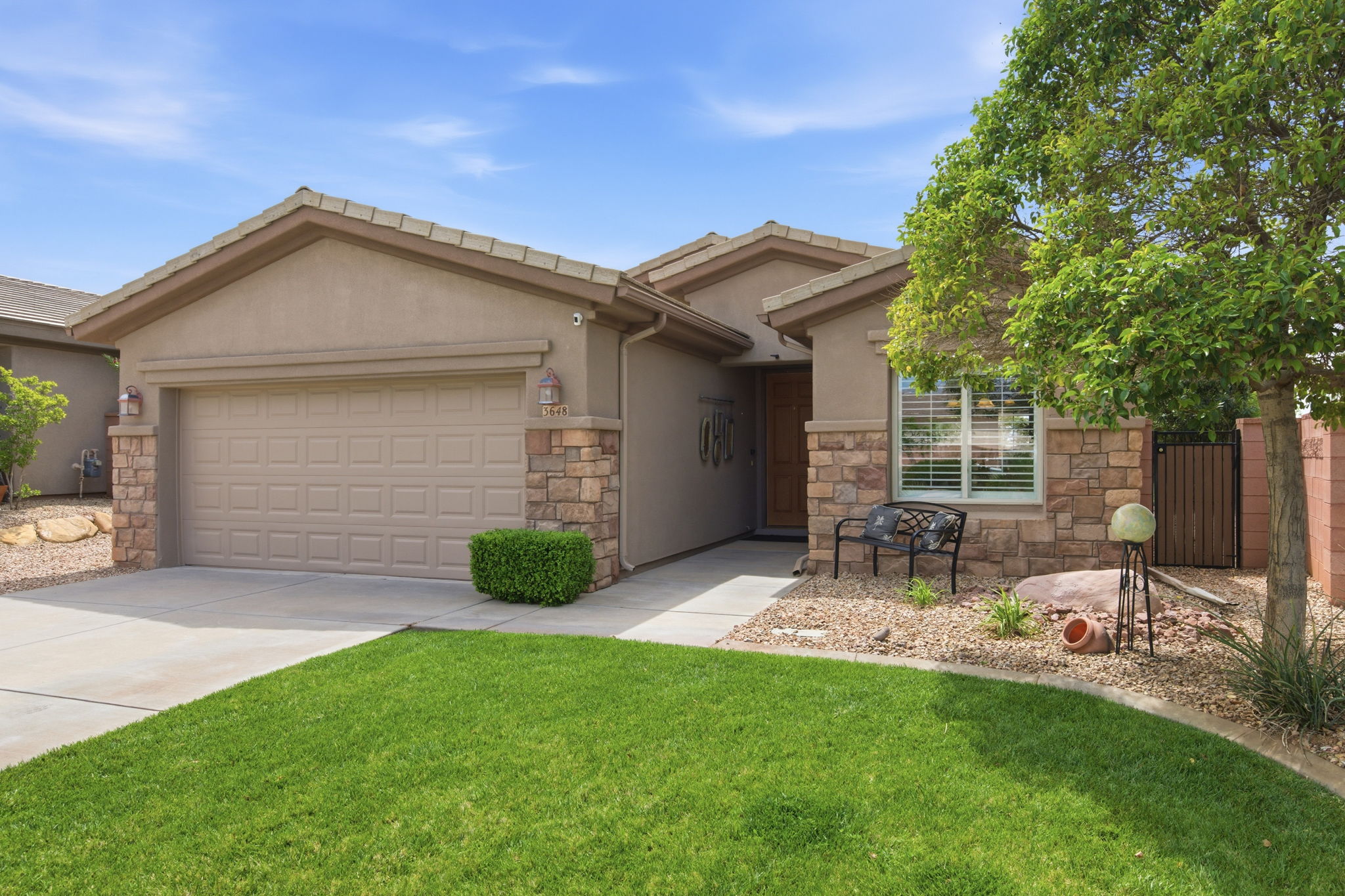 Ranch-style home with an attached garage, driveway, stucco siding, and stone siding